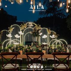 an outdoor garden event space is lit up at night with lights and flowers on the tables