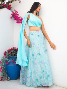 A two-piece Blue floral multi sequins lehenga with light blue drape blouse from the Shrena Hirawat collection. This beautiful cotton satin blue drape blouse is paired with a semi satin georgette blue floral multi sequins lehenga. The multi sequin floral embroidery with cancan, and butter crepe lining enhance this lehenga set. This outfit is completed with a blue dupatta attached to the drape blouse. Blue Lehenga For Spring Party, Spring Blue Fitted Lehenga, Spring Party Lehenga With Traditional Drape, Spring Bollywood Lehenga With Traditional Drape, Festive Light Blue Blouse Piece For Party, Festive Light Blue Blouse For Party, Bollywood Style Light Blue Party Dress, Festive Light Blue Party Blouse, Summer Bollywood Blue Lehenga