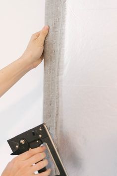 a person is working on a piece of fabric that has been taped to the wall