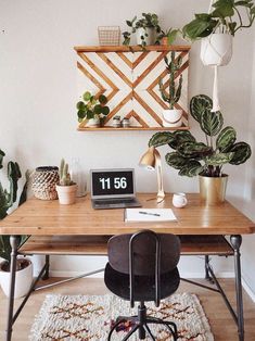 a wooden desk topped with a laptop computer sitting on top of a wooden table next to a potted plant