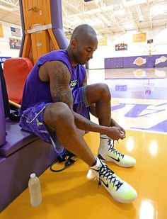 a man sitting on top of a basketball court next to a water bottle and shoes