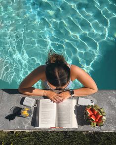 a woman sitting by the pool reading a book