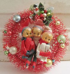 a christmas wreath with three dolls on it