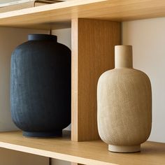 two vases sitting on top of a wooden shelf