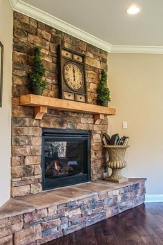 a fireplace with a clock above it and some plants on the mantels in front of it