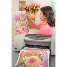 a woman is printing flowers on a large sheet of paper with a printer in front of her