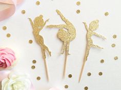 two cake toppers with gold glitter on them, one is a ballerina and the other is a ballet dancer