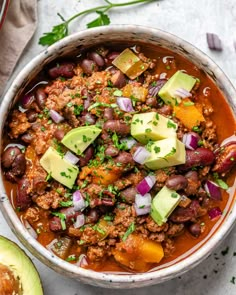 a bowl filled with chili, beans and avocado on top of a table