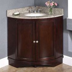 a bathroom vanity with a marble top and wooden cabinet, in front of a gray wall