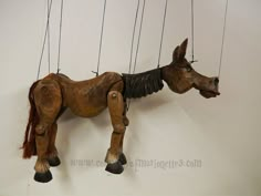 a wooden horse hanging from strings on a wall