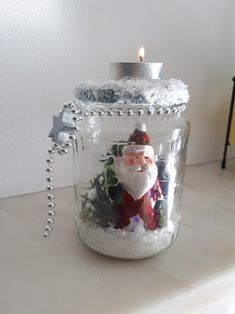 a glass jar filled with snow and a santa clause candle holder sitting on top of a counter