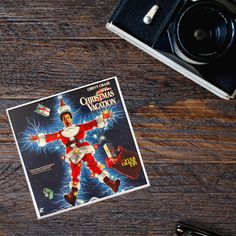 an old fashioned christmas movie poster on a wooden table next to a camera and other items