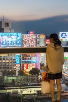 a woman is looking out over the city at night