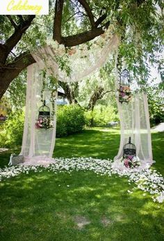 an outdoor ceremony setup with flowers on the ground and white draping over it