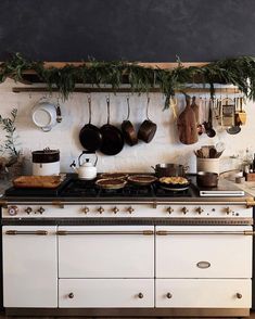 an old fashioned stove with pots and pans hanging on it's wall above the range