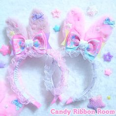 two pink and blue hair accessories laying on top of a white surface with stars around them