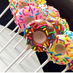 several donuts with sprinkles on them sitting on a white and black rack