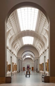 the inside of an art museum with paintings on the walls and vaulted ceiling, along with two benches