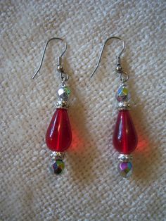 "Beautiful handmade drop earrings measure 2 1/8\" long. The earrings are in a silver tone setting and feature a red center drop bead with silver tone and iridescent beads on top and bottom. These earrings have a lot of sparkle and would dress up any outfit." Red Nickel-free Drop Crystal Earrings, Red Beaded Drop Crystal Earrings, Red Beaded Crystal Drop Earrings, Red Teardrop Earrings With Dangling Beads, Red Beaded Dangle Earrings, Red Beaded Sterling Silver Earrings, Red Metal Dangle Beaded Earrings, Red Metal Drop Beaded Earrings, Red Metal Beaded Drop Earrings