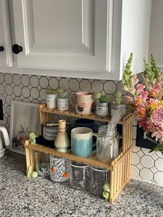 the kitchen counter is full of dishes and cups, with flowers in vases on top