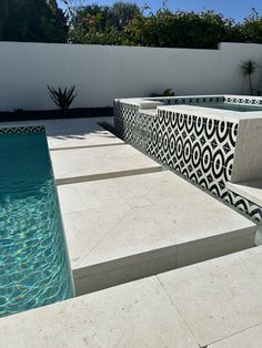 an outdoor swimming pool surrounded by white walls and tiled flooring, with blue water in the middle