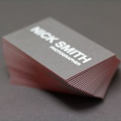 a stack of business cards sitting on top of a gray table next to each other