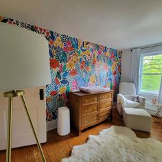 a baby crib in the corner of a room with floral wallpaper on it