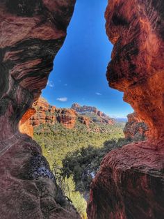 the view from inside a rock formation looking down at trees and mountains