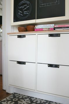 a white cabinet with two drawers and a chalkboard on the wall