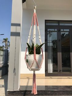 a planter hanging from the side of a building with a pink and white tassel