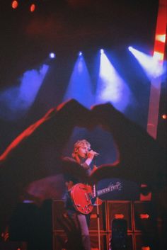 a woman standing on top of a stage holding a red guitar in front of her