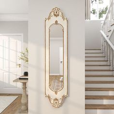 an ornate gold framed mirror on the wall next to a stair case in a white room