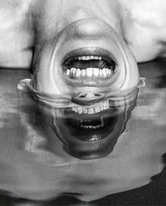 a black and white photo of a dog's mouth with water in the foreground