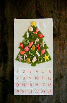 a calendar hanging on a wall with a christmas tree made out of buttons and magnets