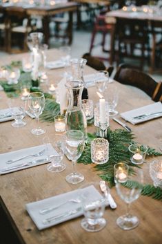 a long table is set with candles and place settings for dinner guests to sit at