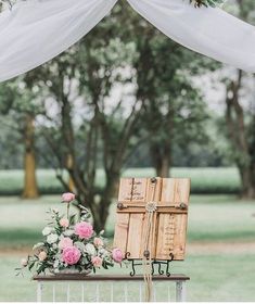 a table with flowers and an open book on it in front of a white drape