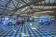 a car is parked in a garage with a boat on the floor and other vehicles