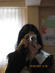 a woman taking a selfie in front of a window holding a camera up to her face