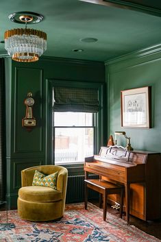 a living room with green walls and a piano in the corner next to a chair