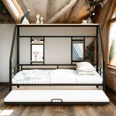 a bed that is in the middle of a room with wood flooring and walls