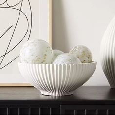 two white vases sitting on top of a table next to an art print and artwork