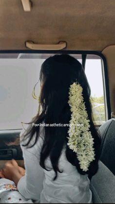 a woman sitting in the back seat of a car with flowers hanging from her hair