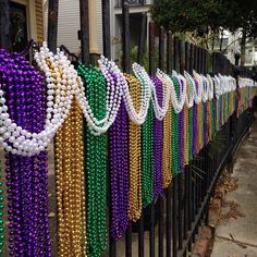 many different colored beads are hanging on a fence