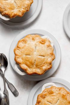 four pies on plates with forks and spoons