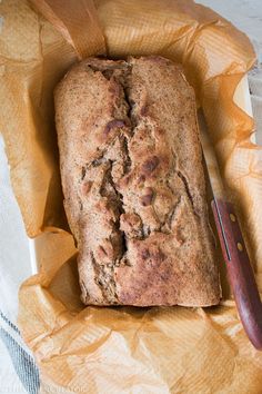 a loaf of bread sitting on top of a piece of paper next to a knife