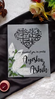 the wedding card has been placed on top of a black satin table cloth with flowers and candles