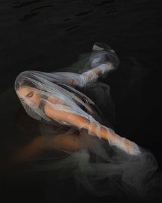 a woman floating in the water wearing a veil