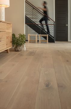 a person is walking up the stairs in a house with wood floors and white walls