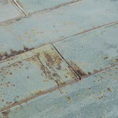 an old blue tile floor with rust on the top and bottom part of it's surface