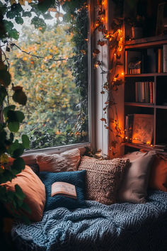 an open book on a couch in front of a window with lights strung from it